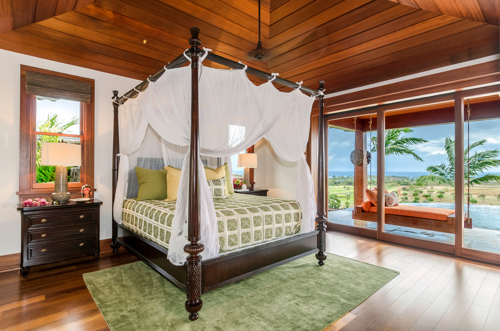 Diseño de dormitorio principal tropical grande sin chimenea con paredes blancas, suelo de madera en tonos medios y suelo marrón