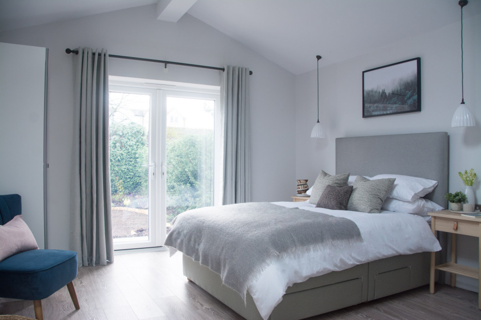 Идея дизайна: гостевая спальня (комната для гостей), среднего размера в стиле неоклассика (современная классика) с серыми стенами, полом из ламината и коричневым полом