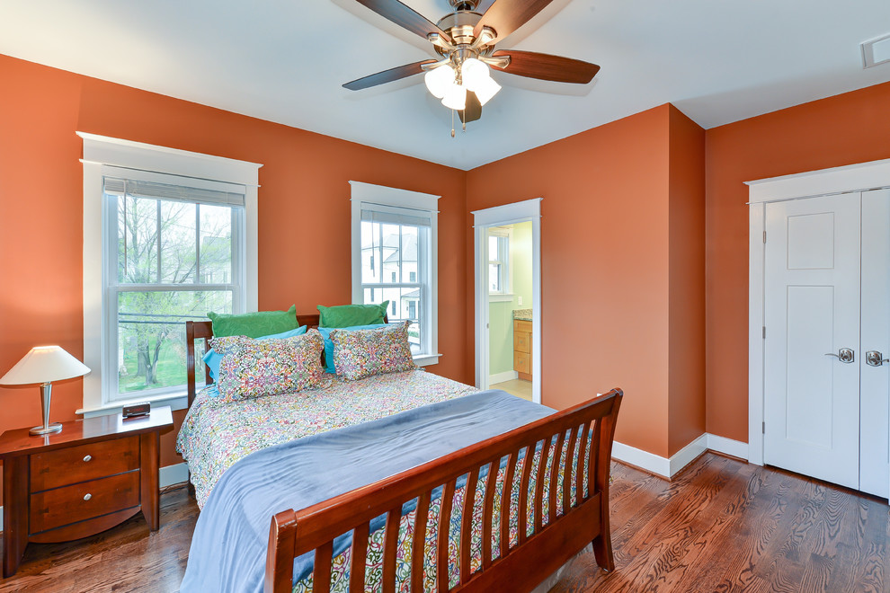Imagen de dormitorio de estilo americano con parades naranjas y suelo de madera en tonos medios