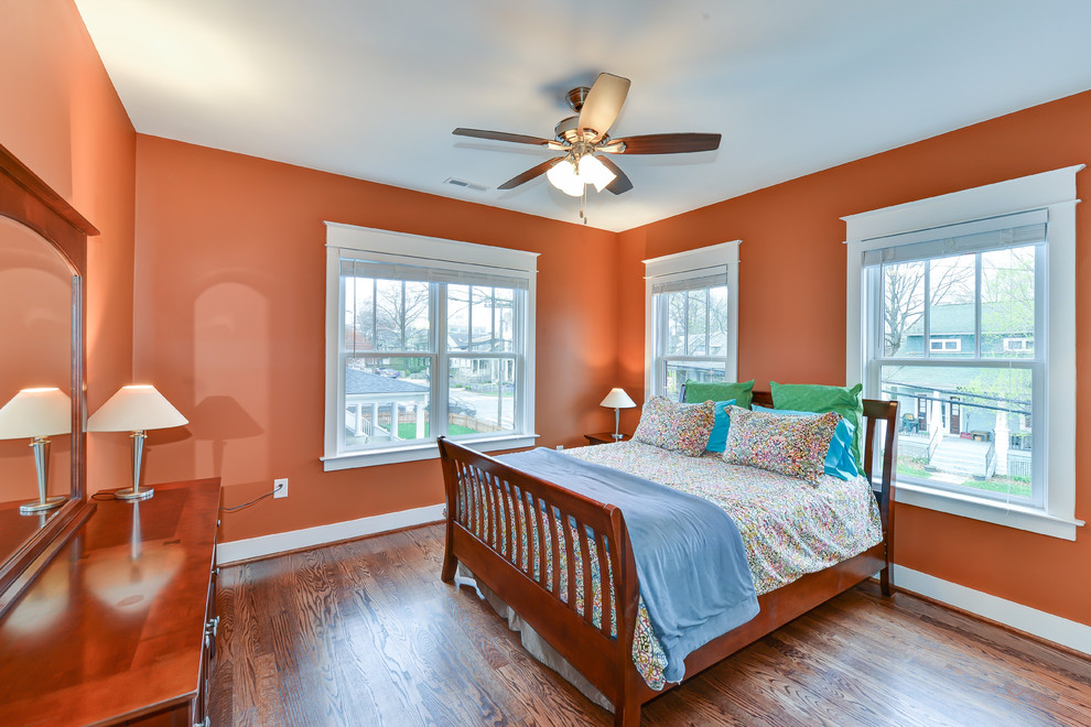 Diseño de dormitorio de estilo americano con parades naranjas y suelo de madera en tonos medios