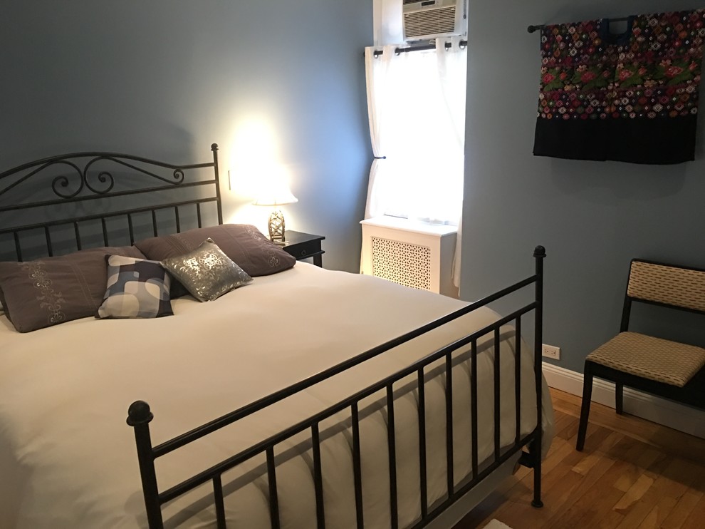 Ejemplo de dormitorio principal bohemio pequeño con paredes azules, suelo de madera en tonos medios y suelo marrón
