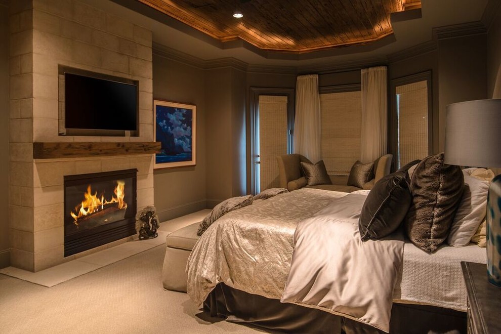 ヒューストンにある広い地中海スタイルのおしゃれな主寝室 (ベージュの壁、カーペット敷き、標準型暖炉、石材の暖炉まわり、ベージュの床) のインテリア
