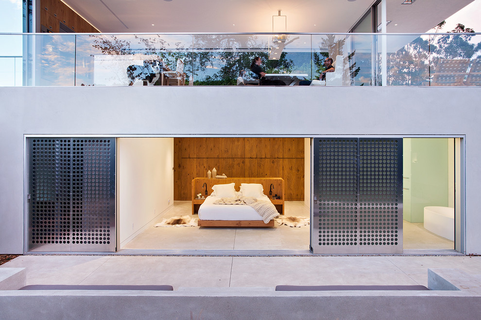 This is an example of a modern master bedroom in San Francisco with white walls, concrete flooring and no fireplace.