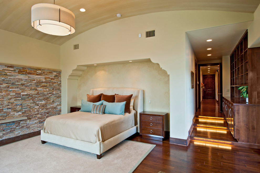 Ejemplo de dormitorio mediterráneo con paredes beige y suelo de madera en tonos medios