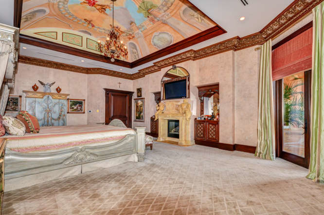 На фото: огромная хозяйская спальня в средиземноморском стиле с разноцветными стенами, ковровым покрытием, стандартным камином, фасадом камина из камня и бежевым полом