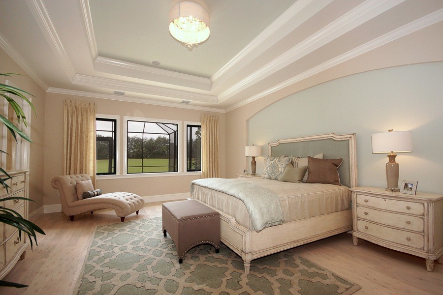 Modelo de dormitorio principal clásico renovado grande con paredes azules, suelo de madera clara y suelo marrón