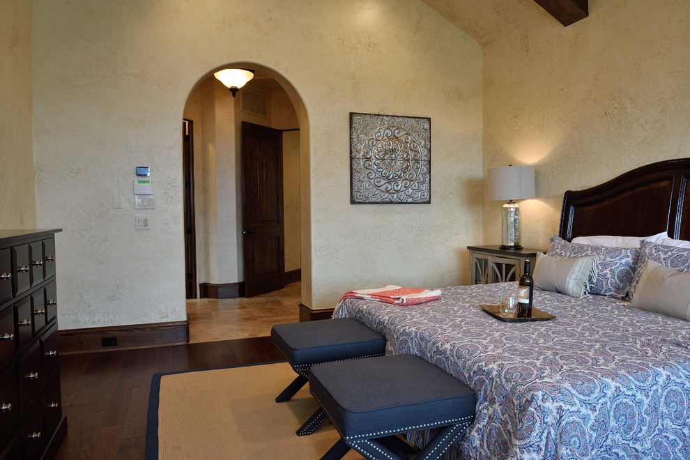 ヒューストンにある広い地中海スタイルのおしゃれな主寝室 (ベージュの壁、無垢フローリング、茶色い床)