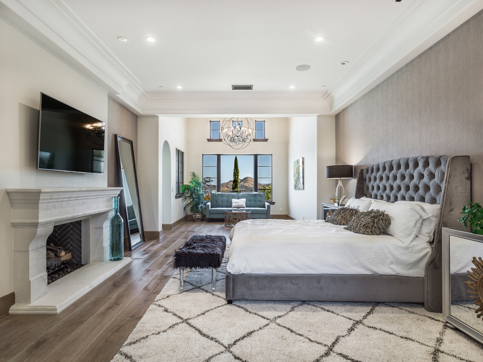 Mediterranes Schlafzimmer mit grauer Wandfarbe, dunklem Holzboden, Kamin, braunem Boden und Tapetenwänden in Los Angeles