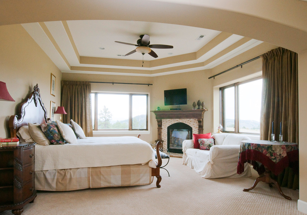 Example of a tuscan master carpeted bedroom design in Denver with beige walls, a corner fireplace and a brick fireplace