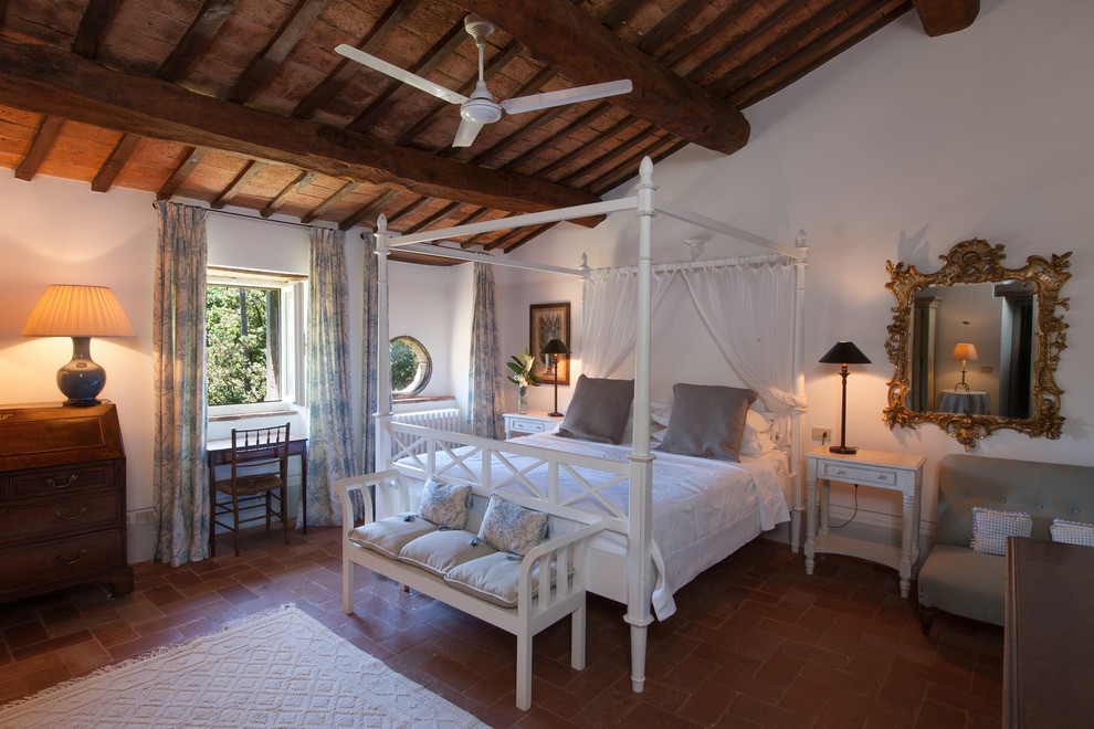 Exemple d'une grande chambre parentale méditerranéenne avec un mur blanc et tomettes au sol.