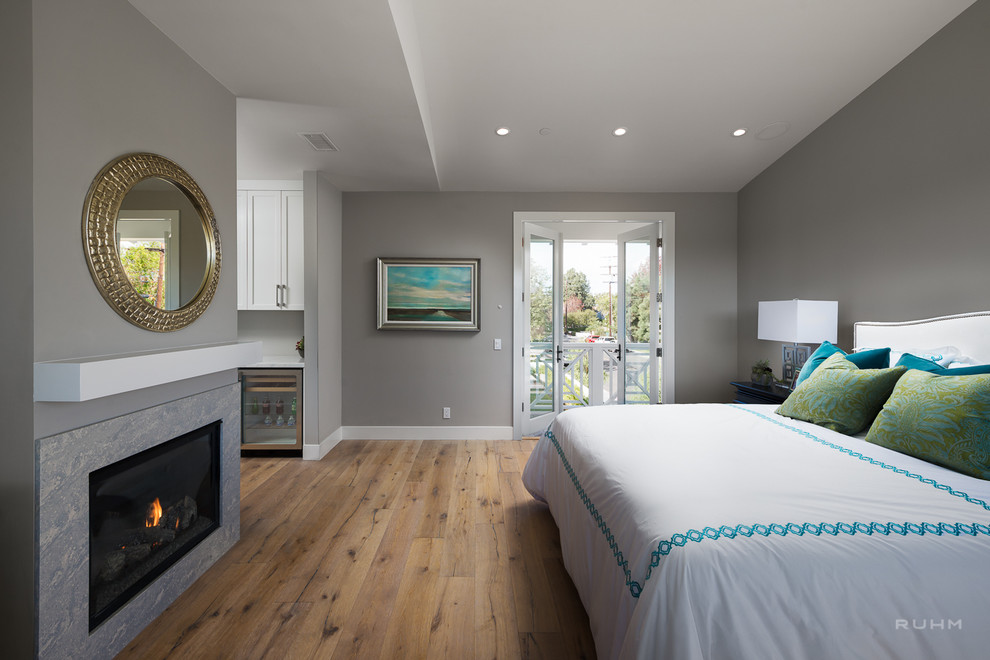 Идея дизайна: хозяйская спальня в современном стиле с серыми стенами, паркетным полом среднего тона, стандартным камином и фасадом камина из камня