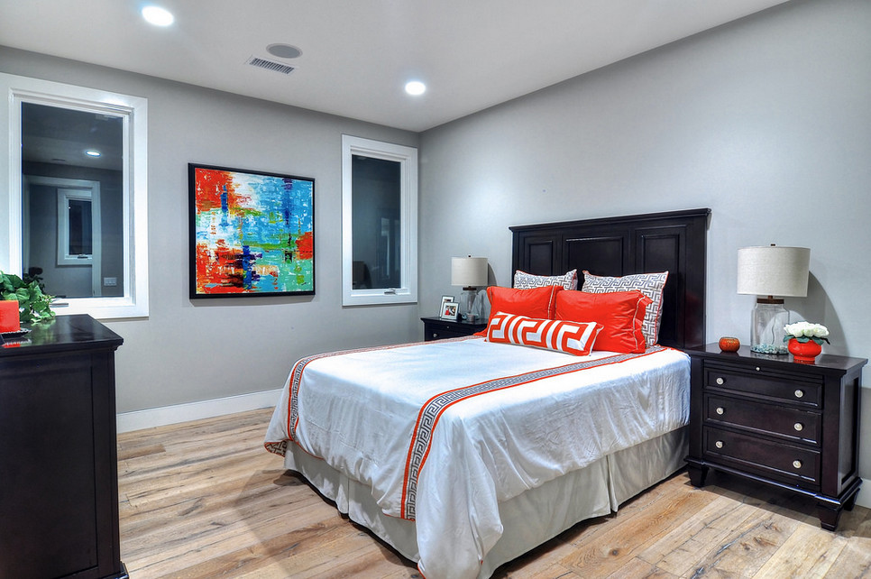 Immagine di una camera degli ospiti di medie dimensioni con pareti grigie e pavimento in legno massello medio