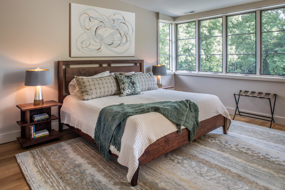 Modelo de dormitorio clásico renovado grande con paredes beige, suelo de madera en tonos medios y suelo marrón