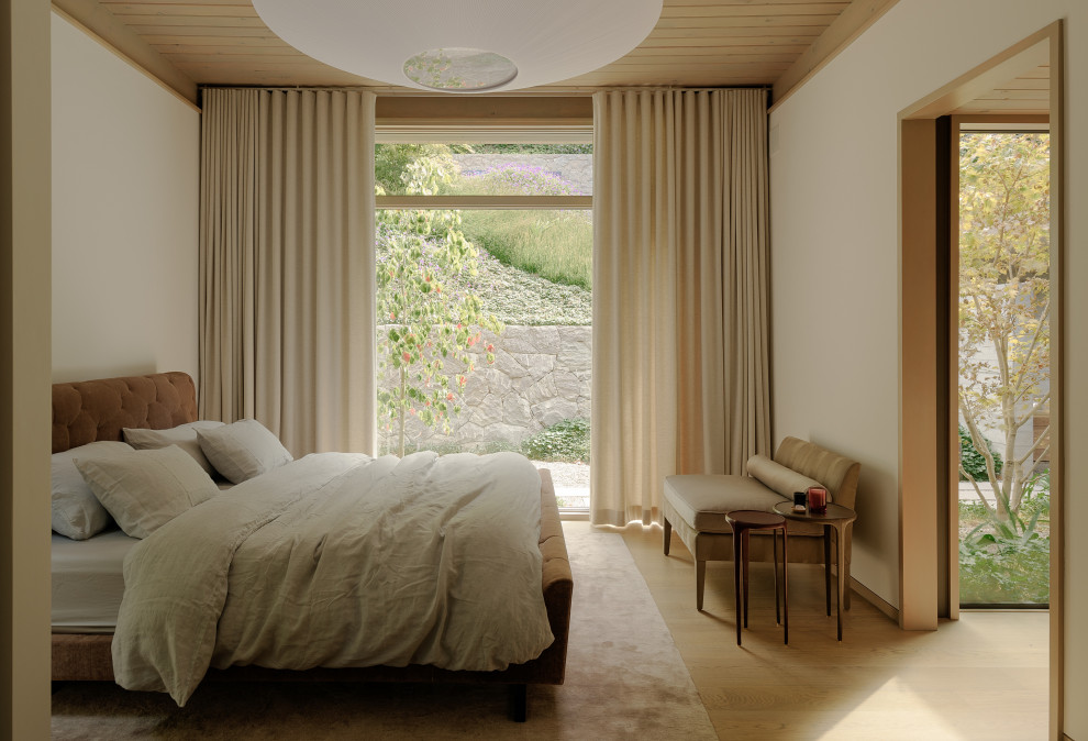 Diseño de dormitorio minimalista con paredes beige, suelo de madera clara y suelo beige