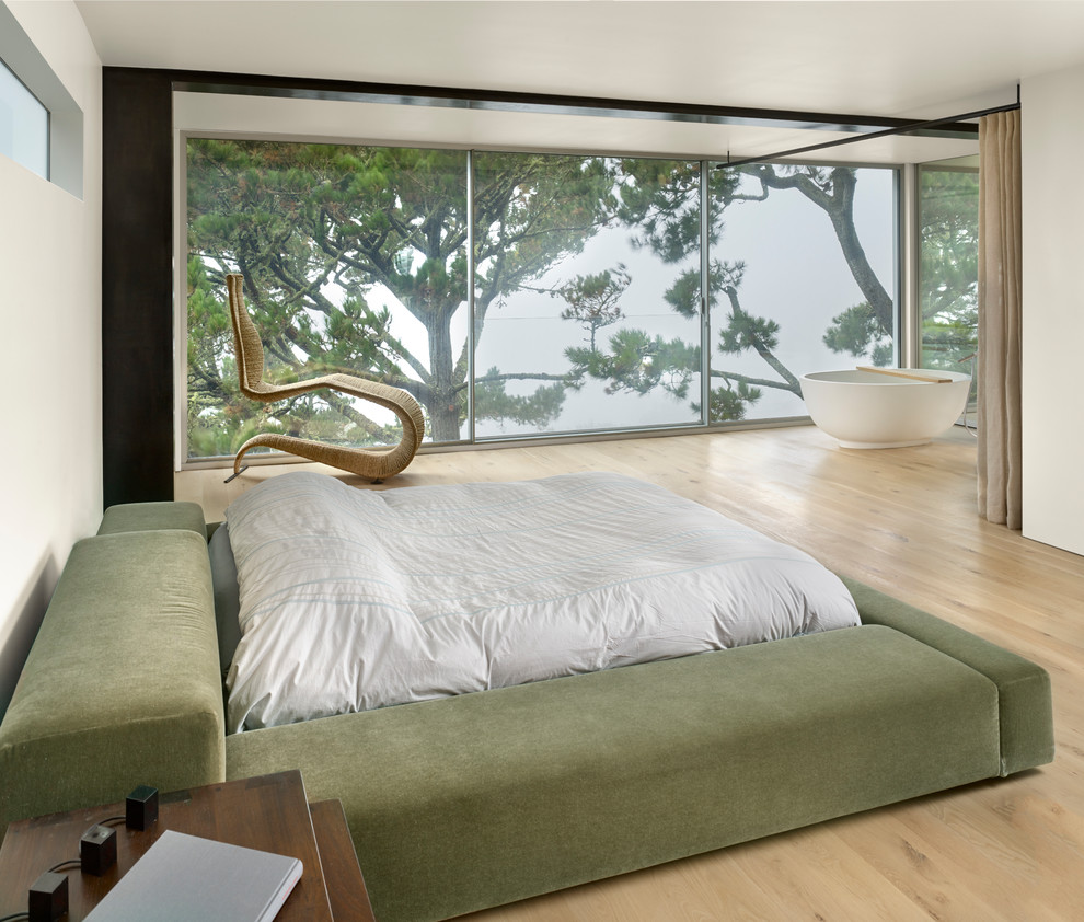 Imagen de dormitorio principal actual de tamaño medio con paredes blancas, suelo laminado y suelo marrón