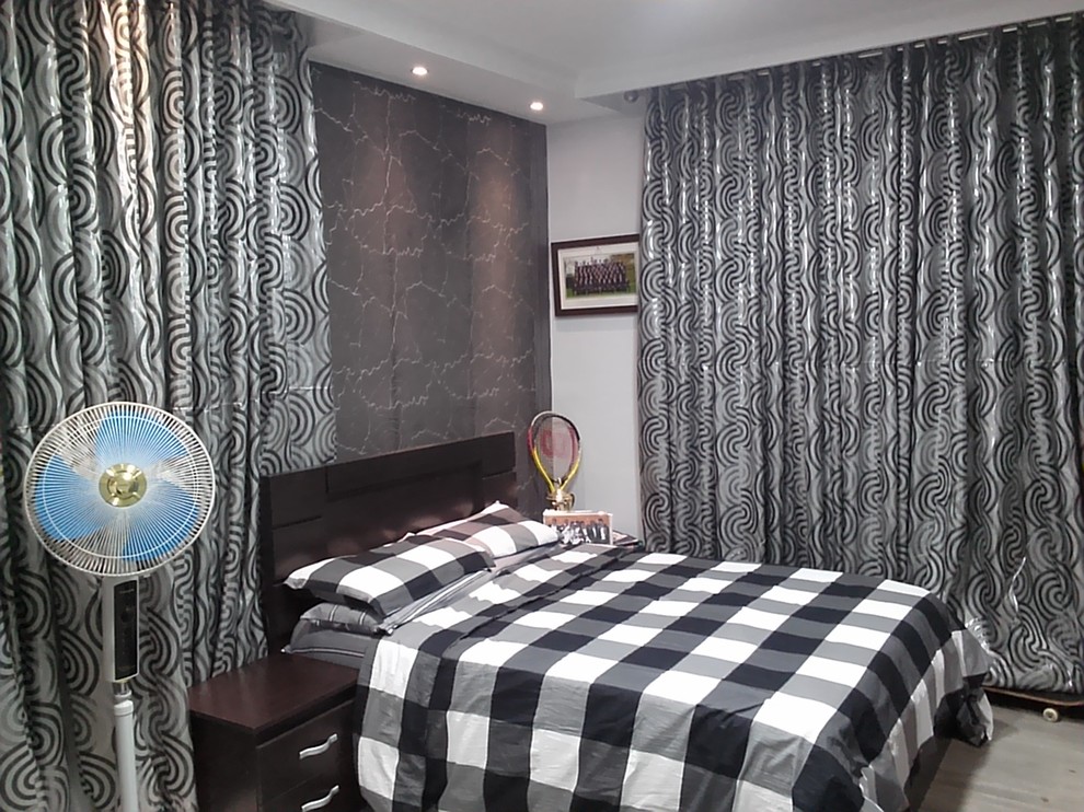 Immagine di una piccola camera da letto minimalista con pareti multicolore e parquet chiaro