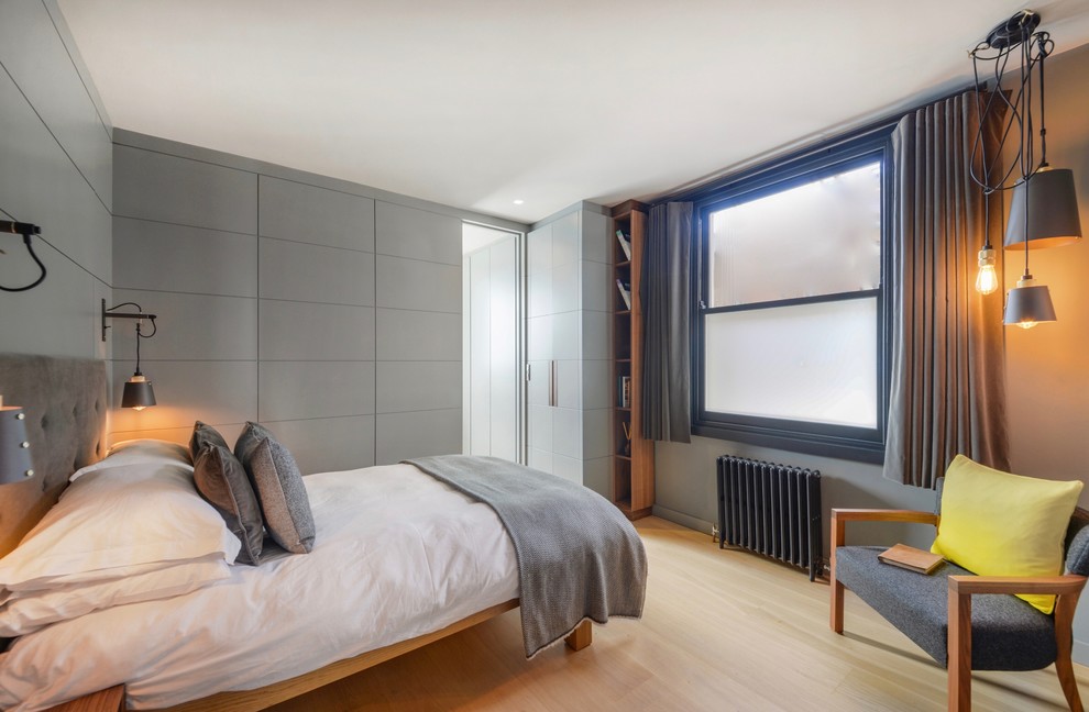 Diseño de habitación de invitados ecléctica pequeña con paredes grises, suelo de madera clara y suelo marrón
