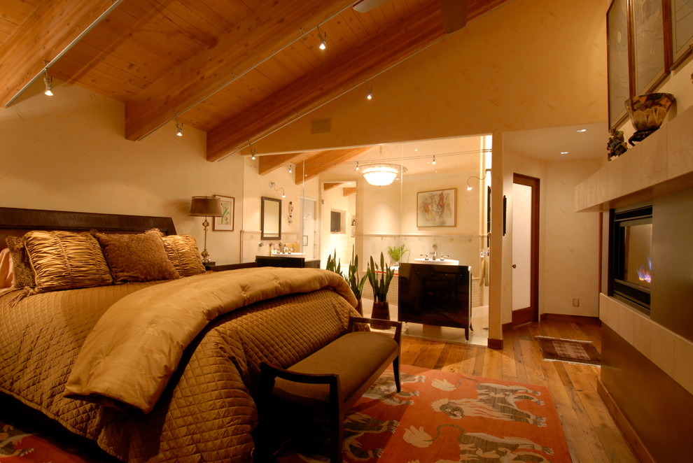 Großes Modernes Hauptschlafzimmer mit beiger Wandfarbe, braunem Holzboden, Kaminumrandung aus Metall und Kamin in Sonstige