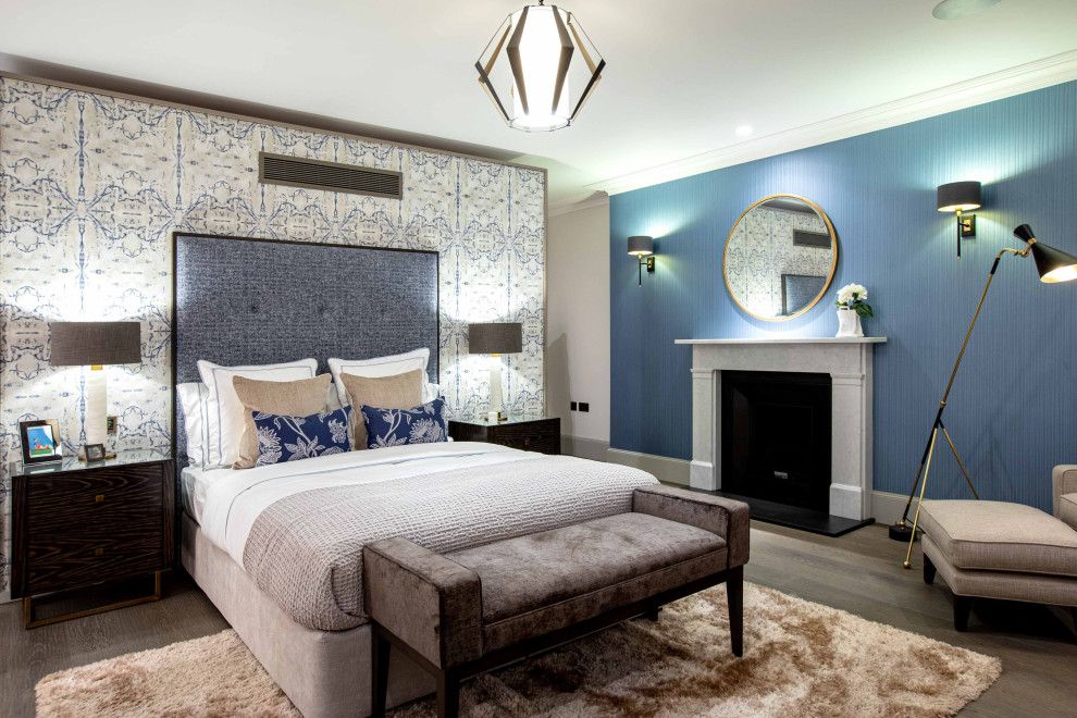 ロンドンにあるトランジショナルスタイルのおしゃれな主寝室 (青い壁、無垢フローリング、標準型暖炉、石材の暖炉まわり、茶色い床、壁紙)