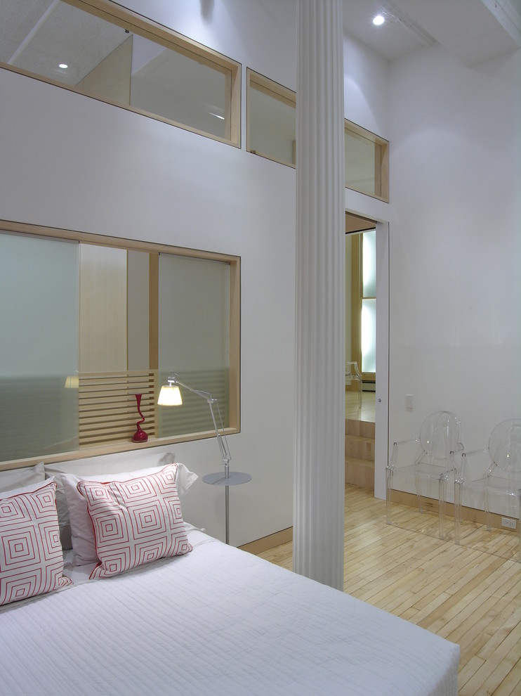 Scandinavian mezzanine loft bedroom in New York with white walls and light hardwood flooring.