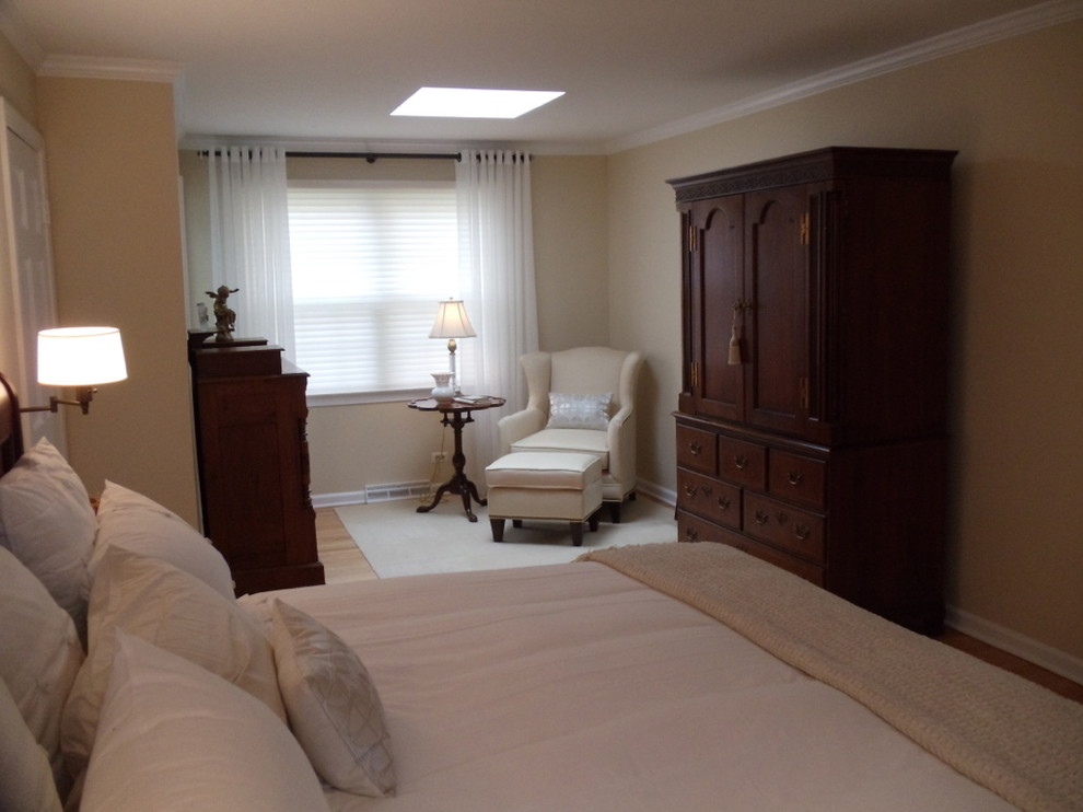 Modelo de dormitorio principal tradicional pequeño con paredes beige y suelo de madera clara
