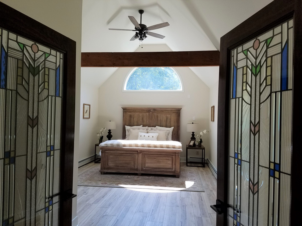Immagine di una piccola camera matrimoniale boho chic con pareti bianche, pavimento in laminato, pavimento grigio e travi a vista