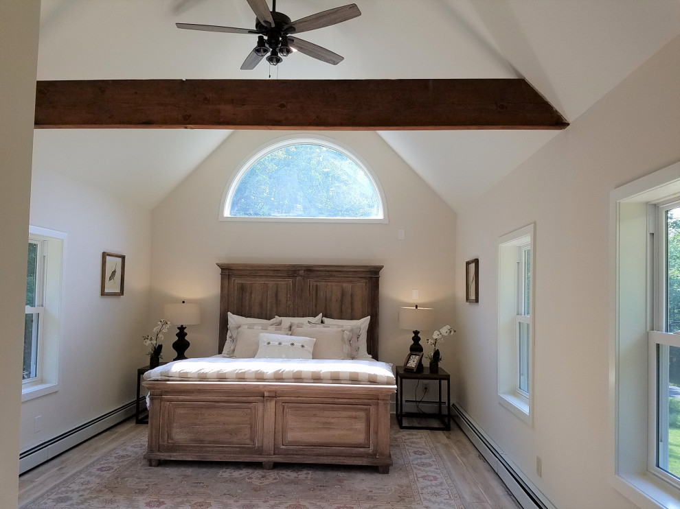 Small eclectic master bedroom in Philadelphia with white walls, laminate floors, grey floors and exposed beams.