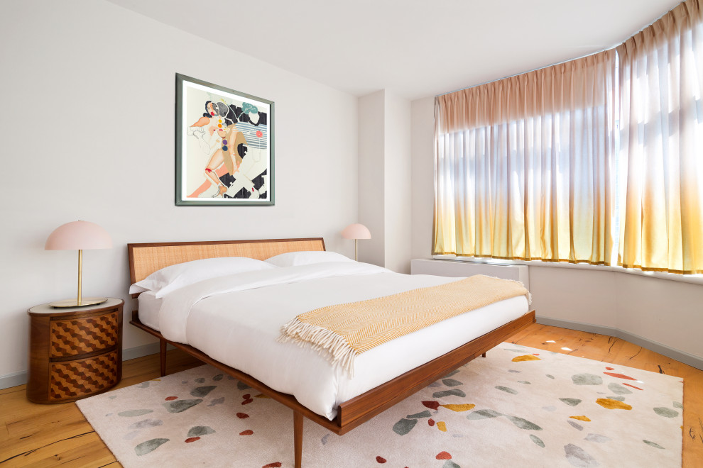 Trendy medium tone wood floor and brown floor bedroom photo in New York with white walls