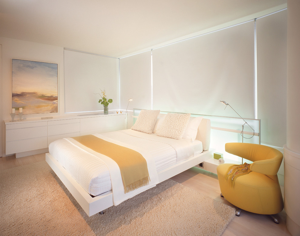 Contemporary bedroom in New York with white walls and light hardwood flooring.