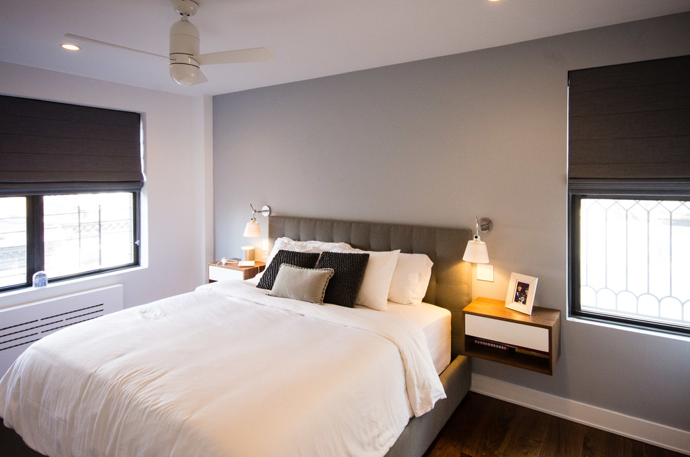 Modelo de dormitorio principal contemporáneo extra grande sin chimenea con paredes blancas, suelo de madera en tonos medios y suelo marrón