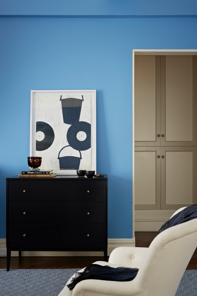 Cette image montre une grande chambre parentale bohème avec un mur bleu, un sol en bois brun et un sol marron.