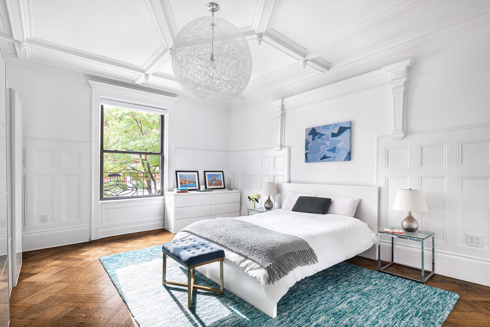 Klassisches Schlafzimmer mit weißer Wandfarbe, braunem Holzboden, braunem Boden und Kassettendecke in New York