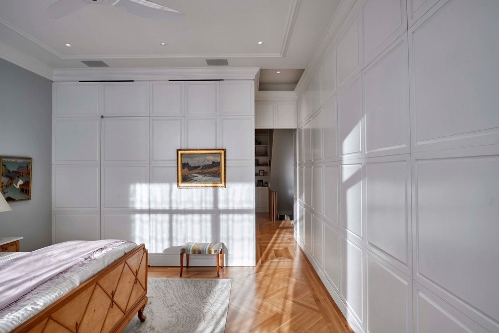 Idée de décoration pour une chambre parentale tradition de taille moyenne avec un mur bleu, parquet clair et un sol beige.