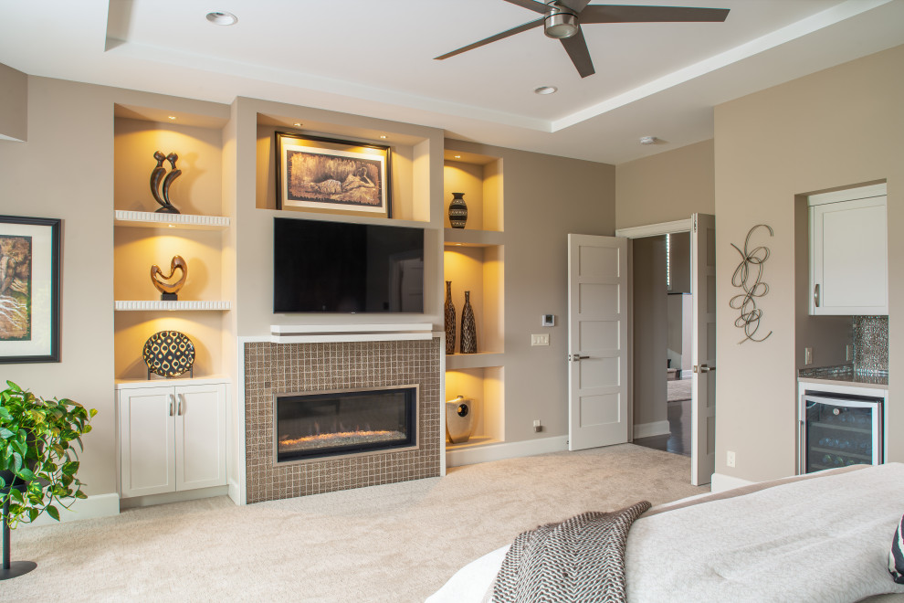 オマハにある広いトランジショナルスタイルのおしゃれな主寝室 (茶色い壁、カーペット敷き、横長型暖炉、タイルの暖炉まわり、グレーの床、グレーとブラウン) のインテリア