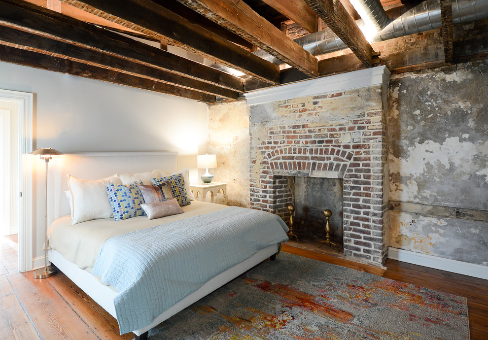 На фото: гостевая спальня (комната для гостей) в стиле лофт с белыми стенами, паркетным полом среднего тона, стандартным камином, фасадом камина из кирпича и коричневым полом с
