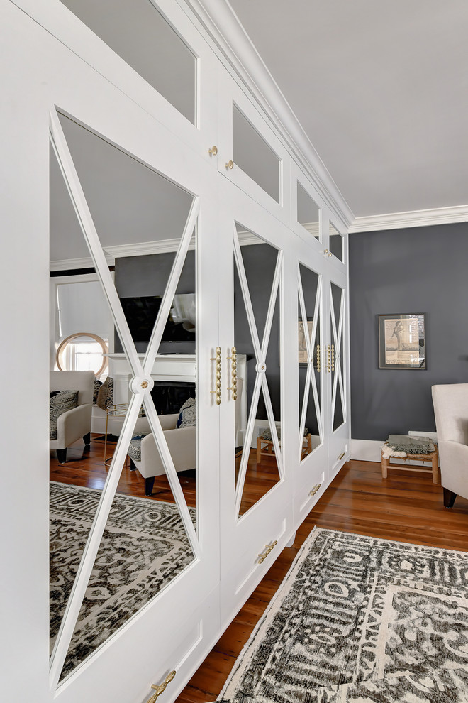 Mittelgroßes Modernes Hauptschlafzimmer mit grauer Wandfarbe, dunklem Holzboden, Kamin, Kaminumrandung aus Holz und braunem Boden in Charleston