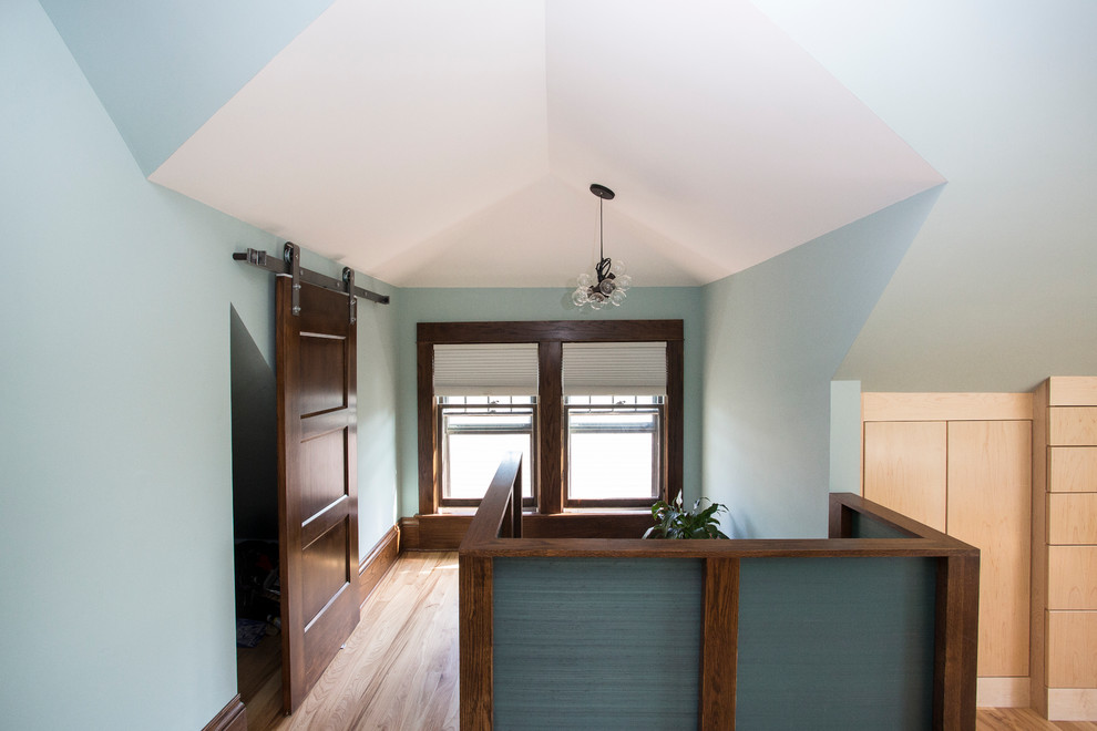 Diseño de dormitorio tipo loft contemporáneo grande con paredes azules y suelo de madera clara