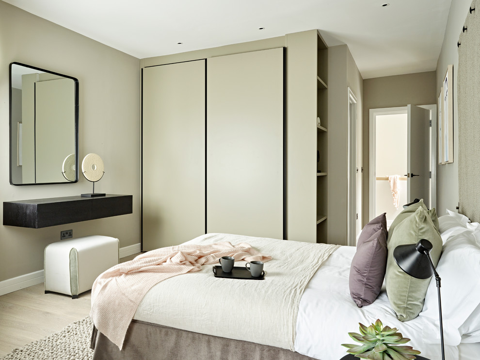 Imagen de habitación de invitados contemporánea de tamaño medio sin chimenea con suelo beige, suelo de madera clara y paredes grises