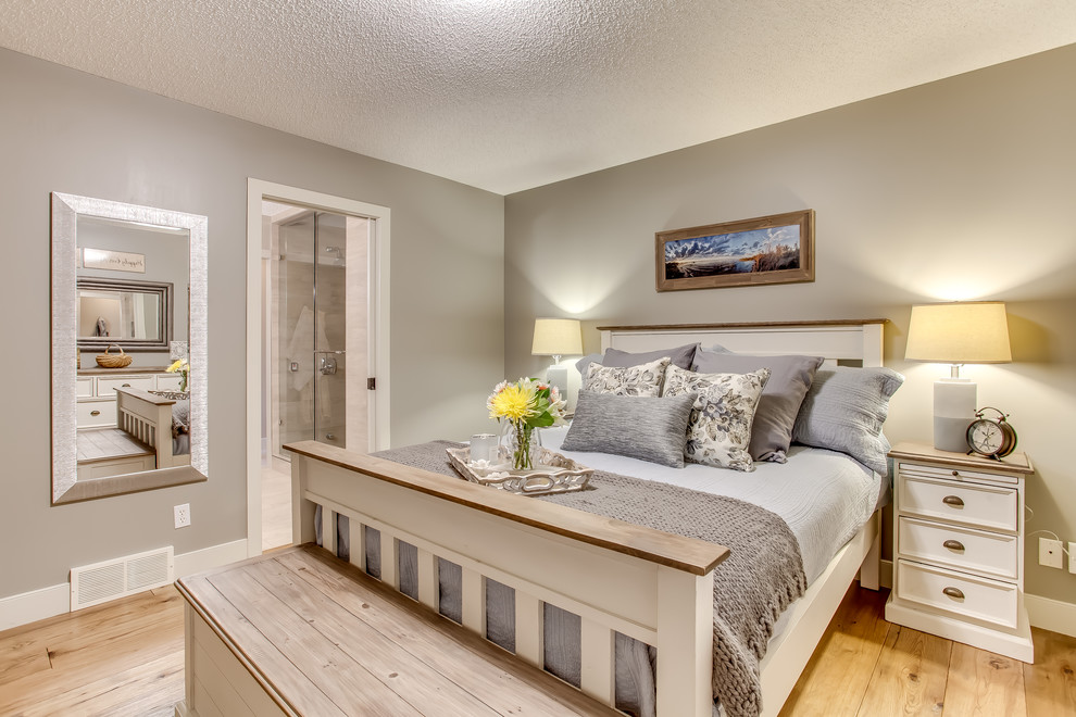 Immagine di una camera matrimoniale country di medie dimensioni con pareti beige e pavimento in legno massello medio