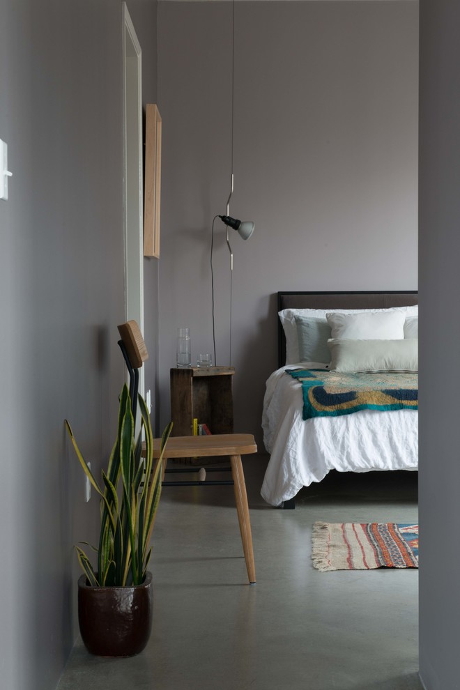 На фото: хозяйская спальня среднего размера в стиле лофт с серыми стенами и бетонным полом без камина