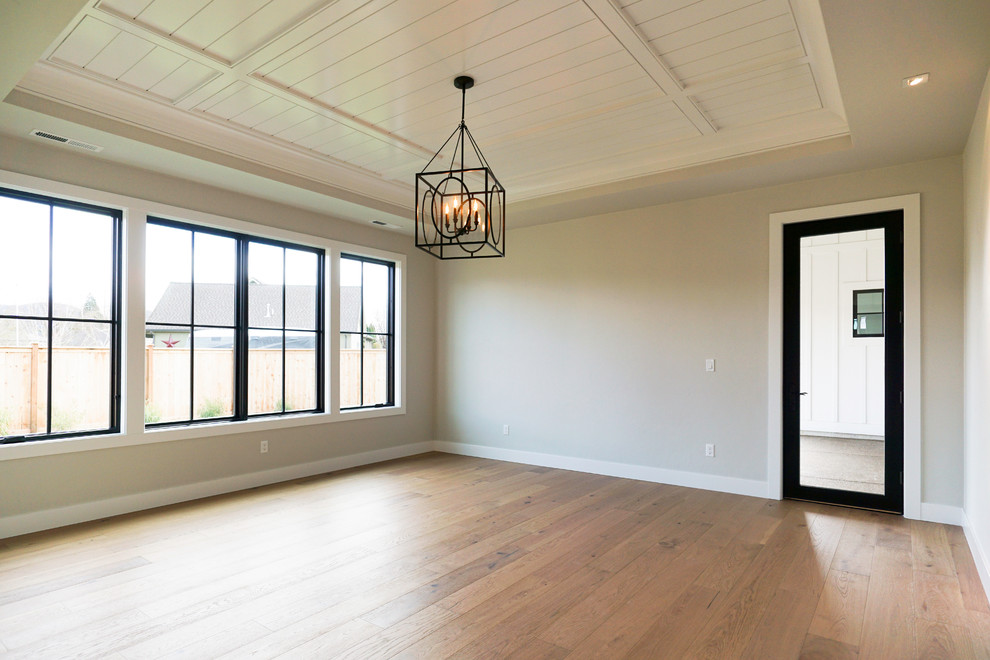 Medium sized farmhouse master bedroom in Portland with grey walls, light hardwood flooring and multi-coloured floors.