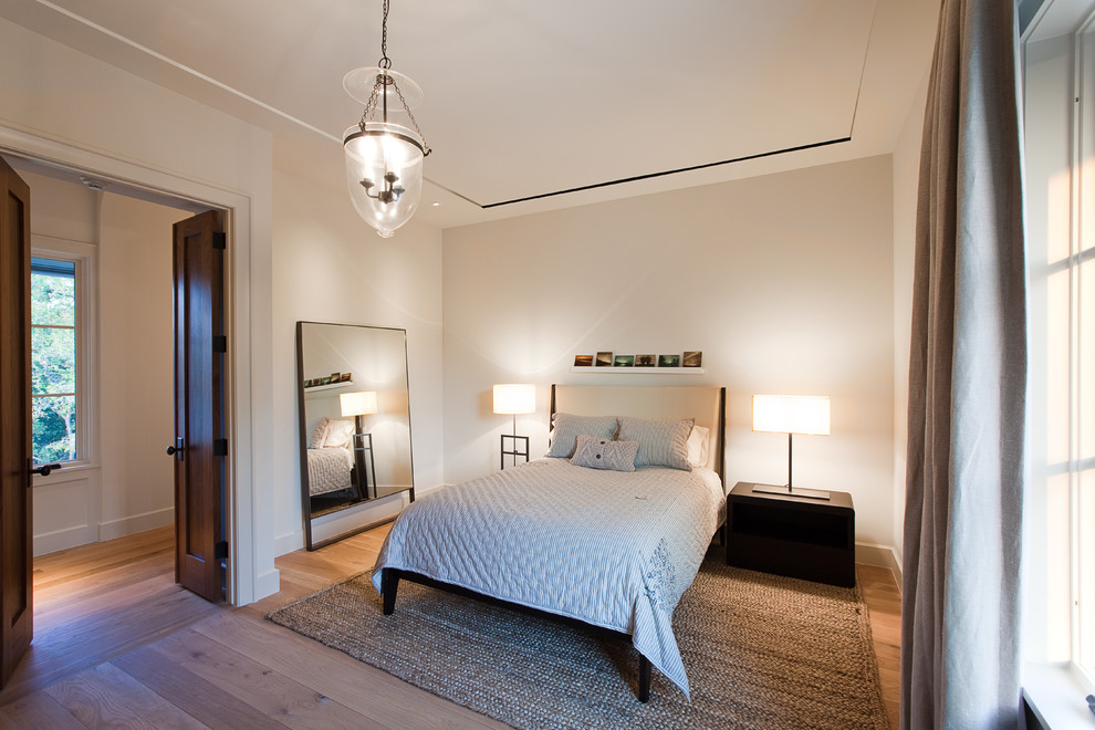 Elegant medium tone wood floor bedroom photo in Austin with beige walls