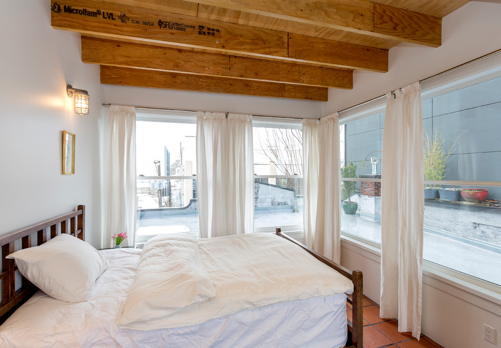 Idee per una camera da letto industriale con pareti bianche e pavimento in terracotta