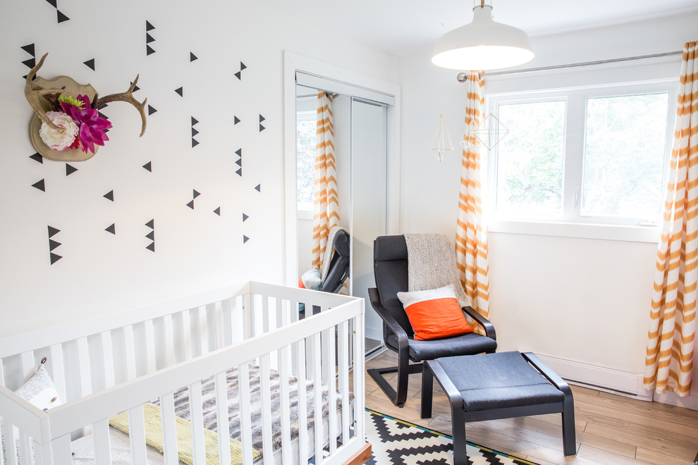 Imagen de habitación de bebé minimalista de tamaño medio con paredes blancas y suelo de madera en tonos medios