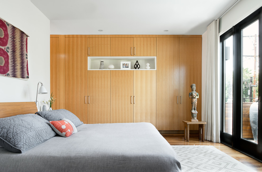 Contemporary bedroom in Los Angeles with white walls and dark hardwood flooring.