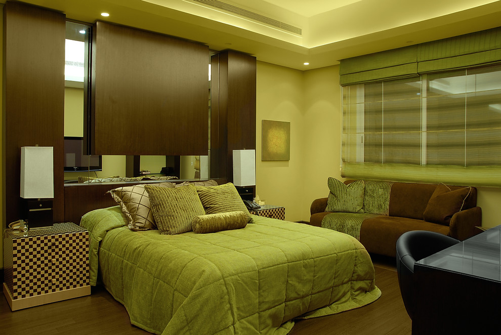 Idée de décoration pour une chambre design avec un mur vert et parquet foncé.