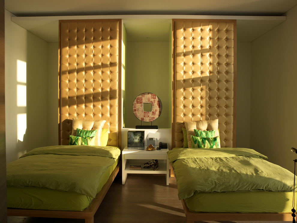 This is an example of a contemporary guest bedroom in Other with green walls, medium hardwood flooring and no fireplace.