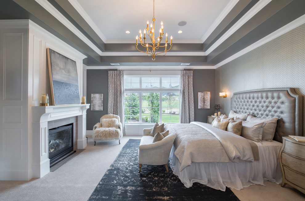 На фото: хозяйская спальня в стиле неоклассика (современная классика) с серыми стенами, ковровым покрытием, стандартным камином и фасадом камина из дерева с