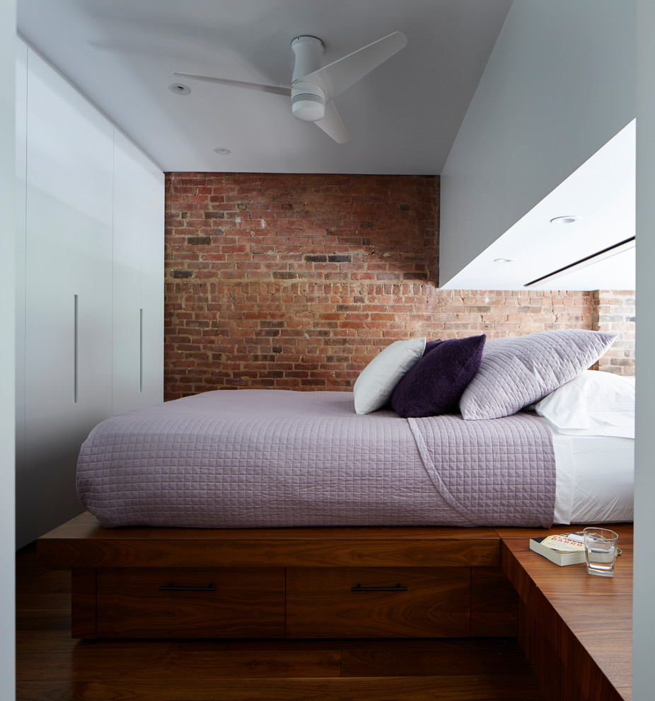 Kleines Modernes Schlafzimmer ohne Kamin, im Loft-Style mit weißer Wandfarbe, braunem Holzboden und blauem Boden in New York
