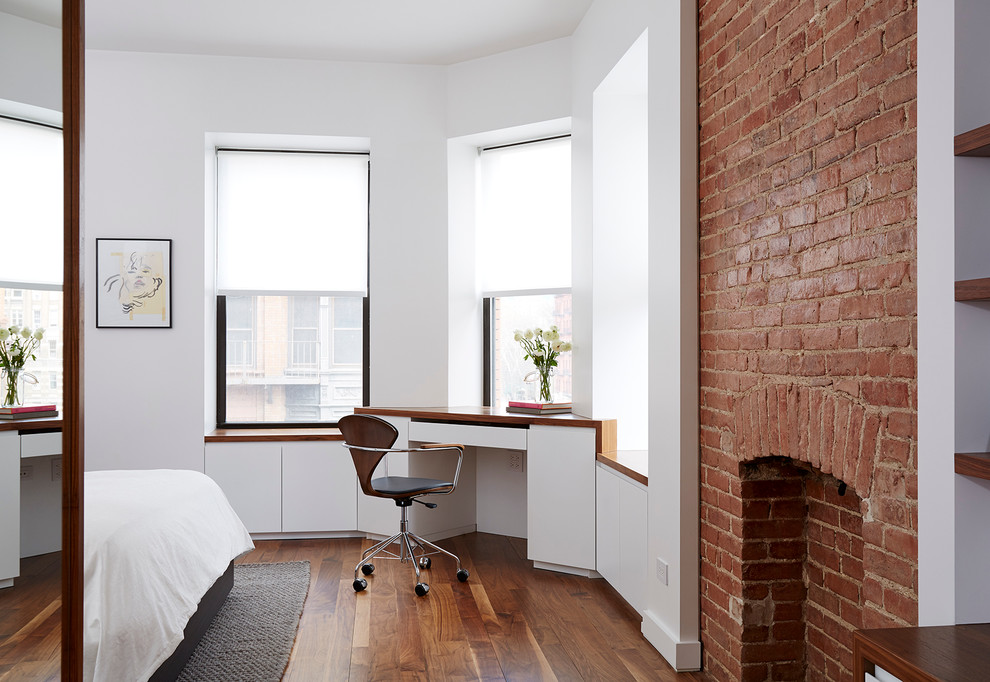 This is an example of a medium sized modern master bedroom in New York with white walls, medium hardwood flooring, a standard fireplace and a brick fireplace surround.